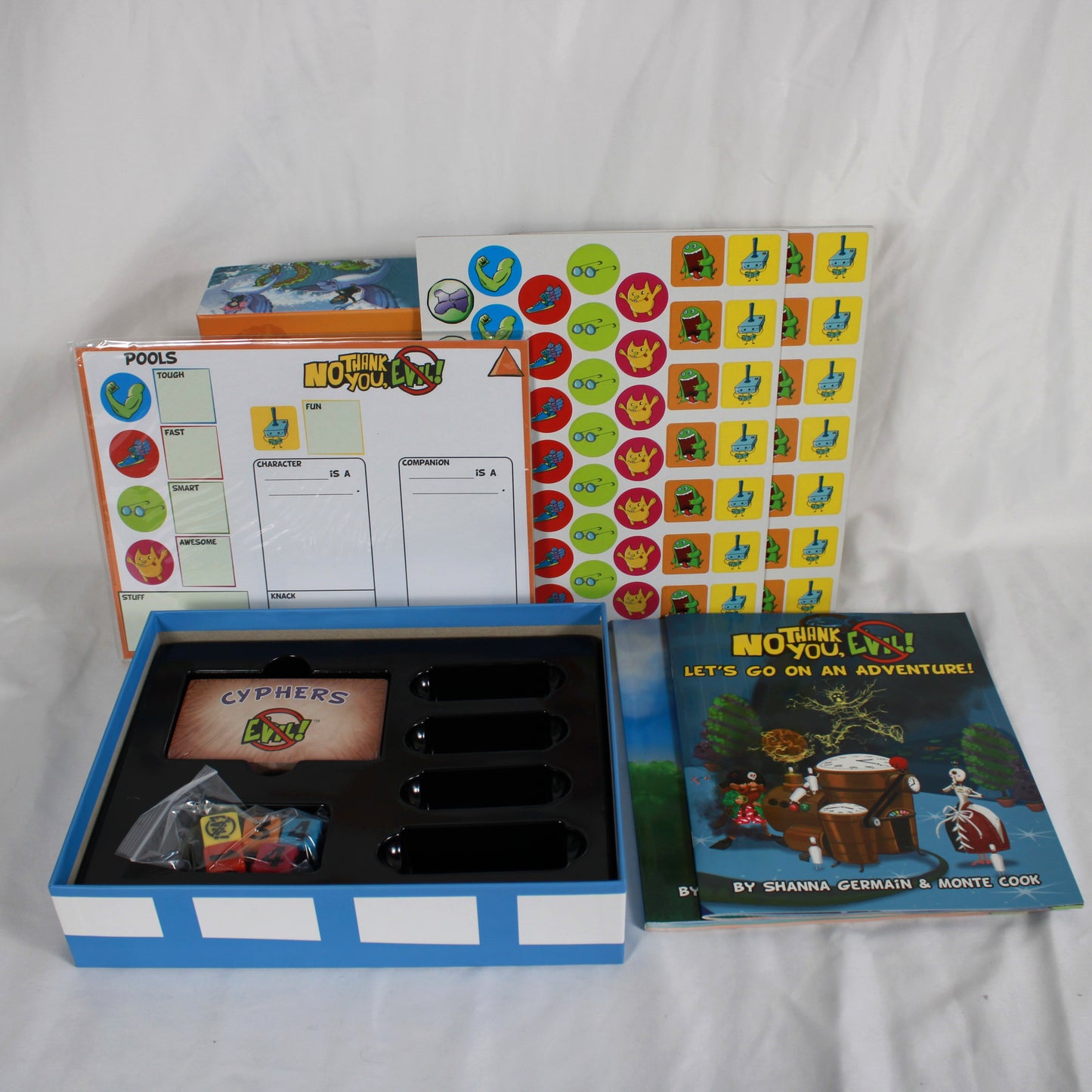 Collection of board game components including a book, cards, and dice on a white background