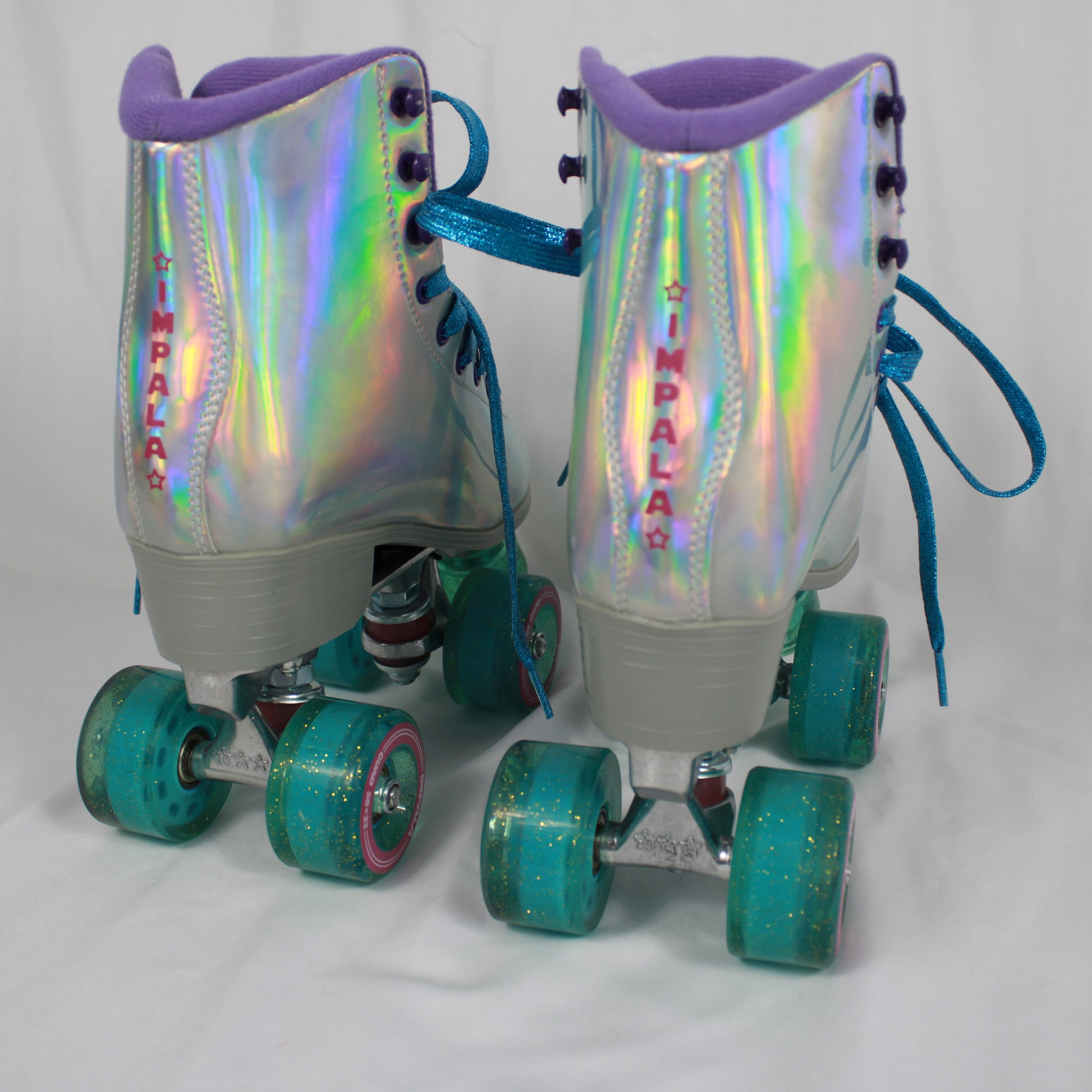 Pair of holographic roller skates with teal wheels on a white background
