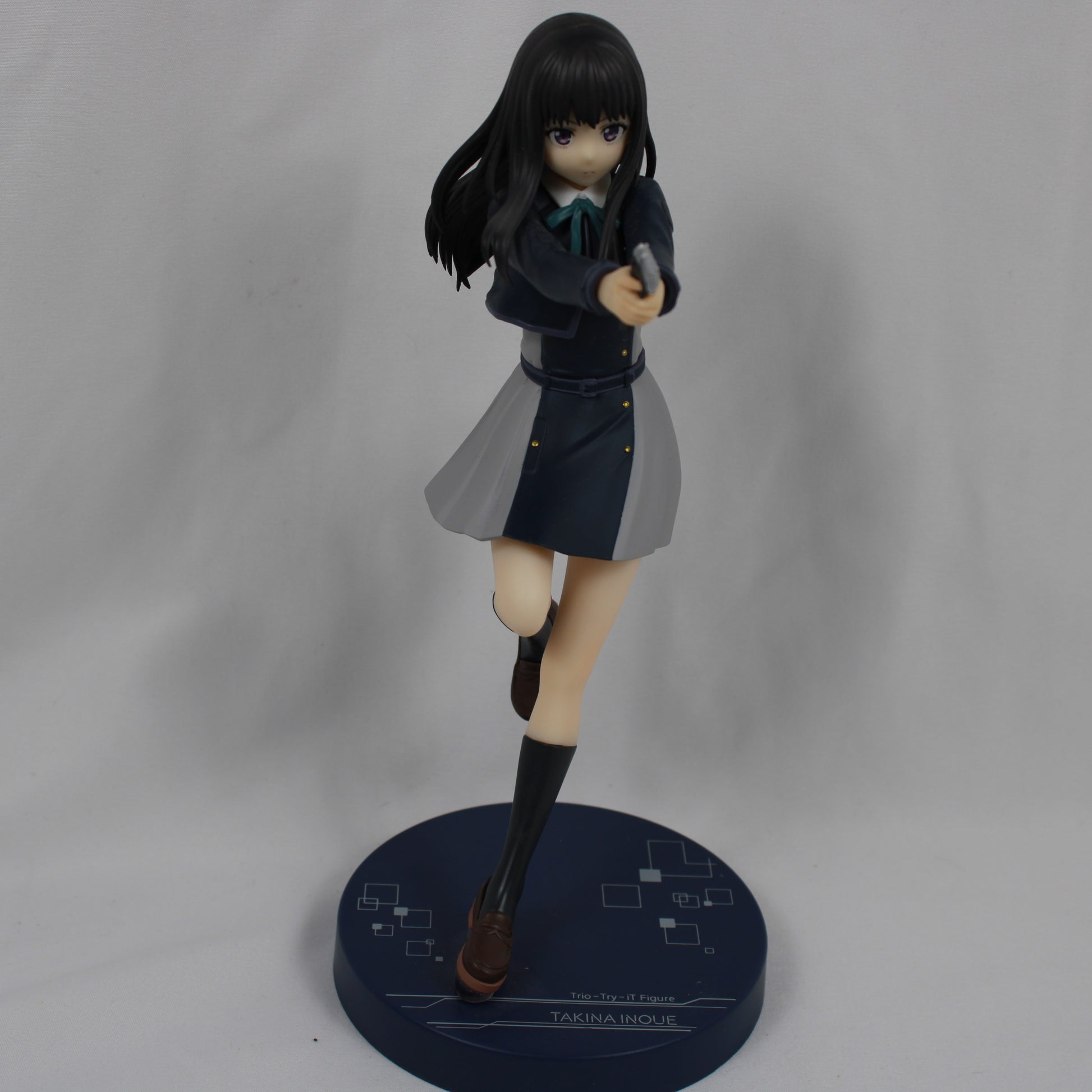 Figurine of a character in a school uniform holding a gun on a gray background
