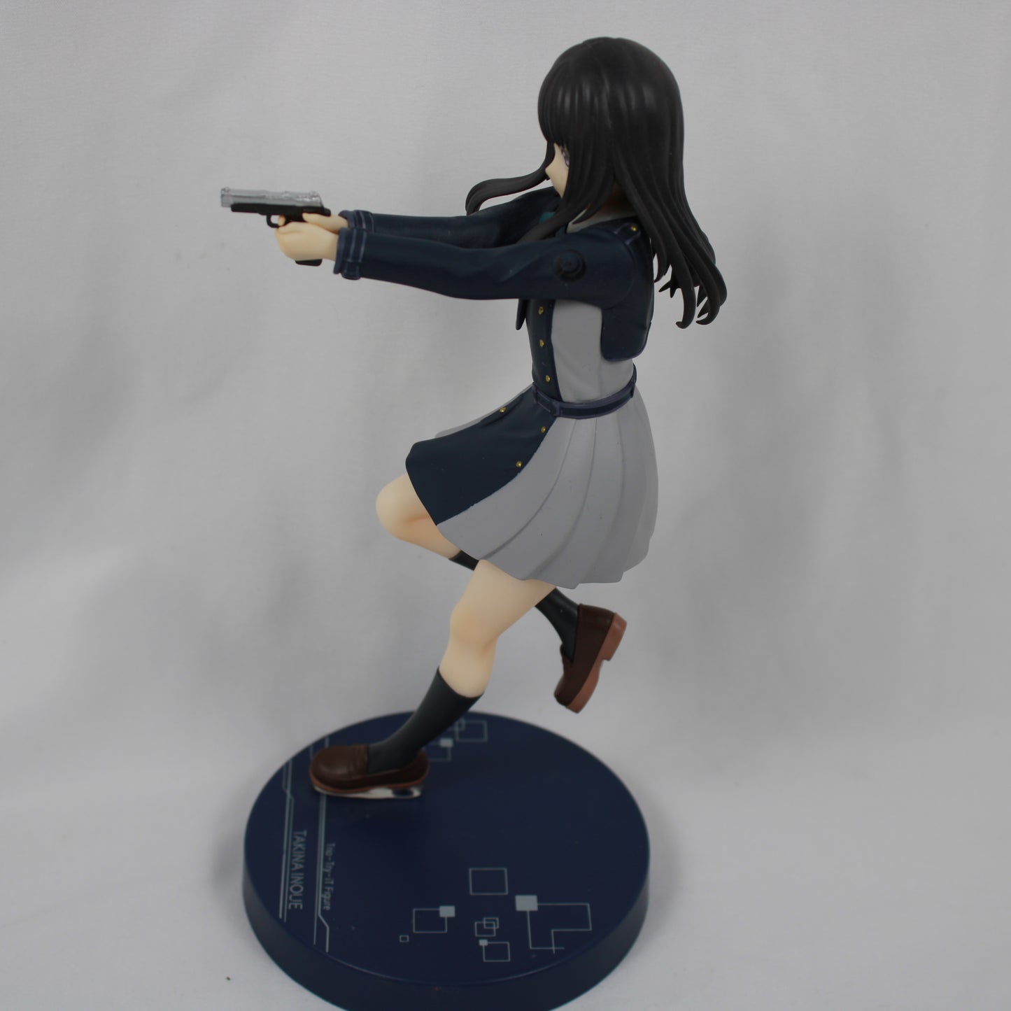 Figure of a character in a dynamic pose with a gun on a gray background