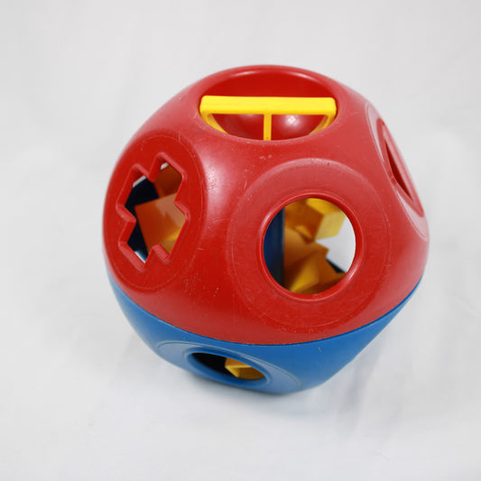 Red and blue plastic ball with cutout shapes on a white background