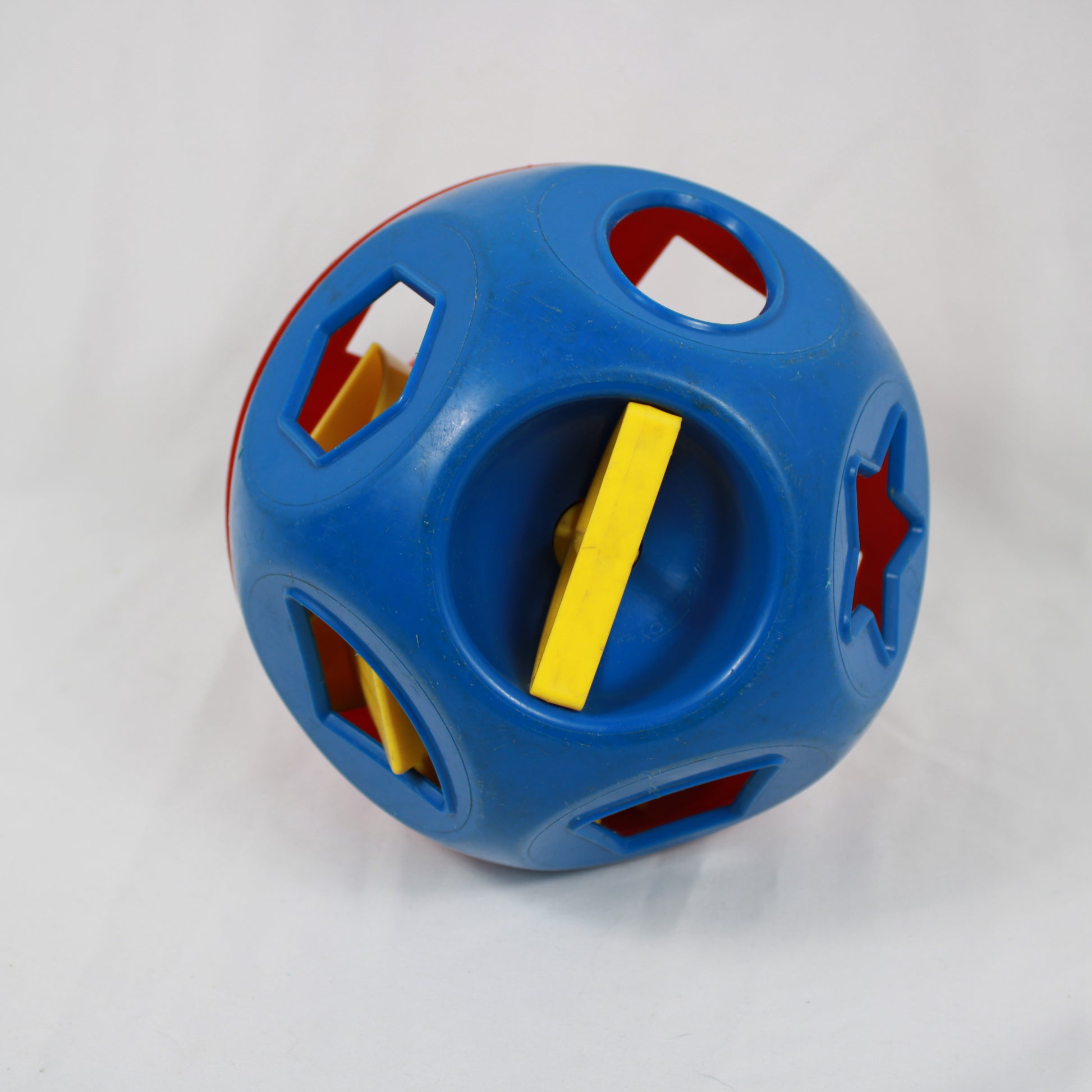 Blue toy with cut-out shapes and a yellow bar on a white background