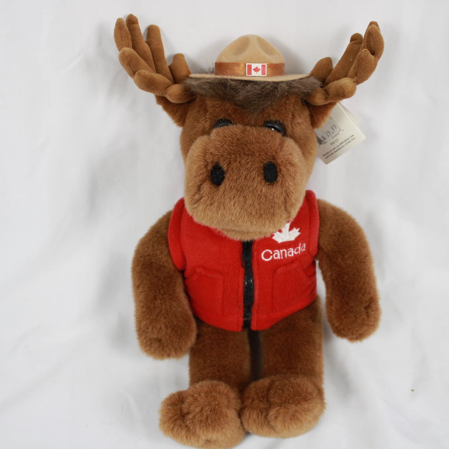 Plush moose toy wearing a red vest and hat with a Canadian flag, on a white background.