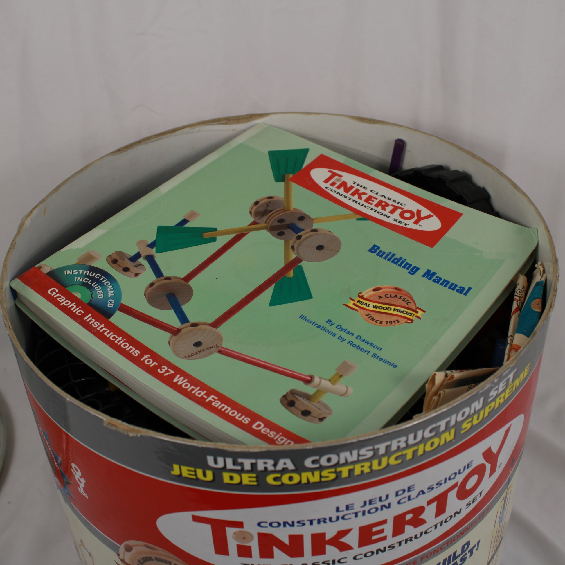 Tinkertoy building set with instructions in a metal can on a white background