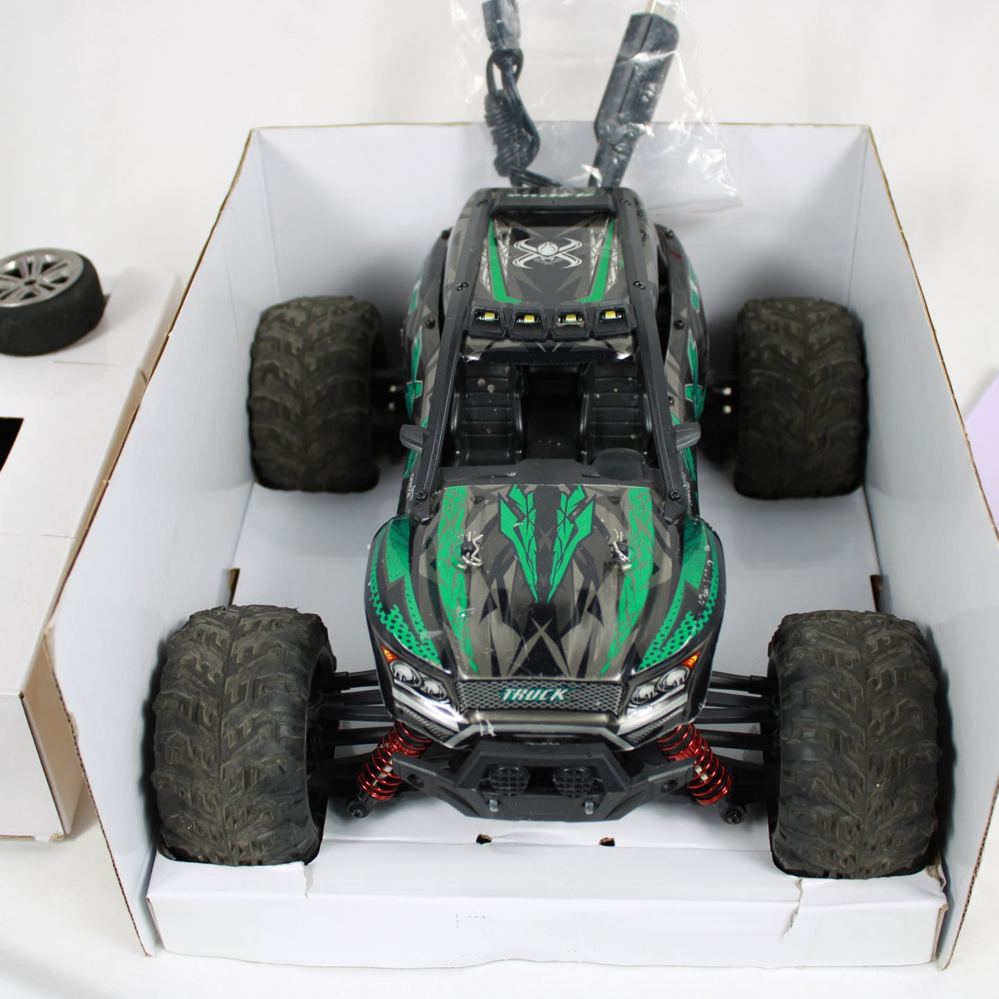 Model off-road vehicle in a box with green and black design