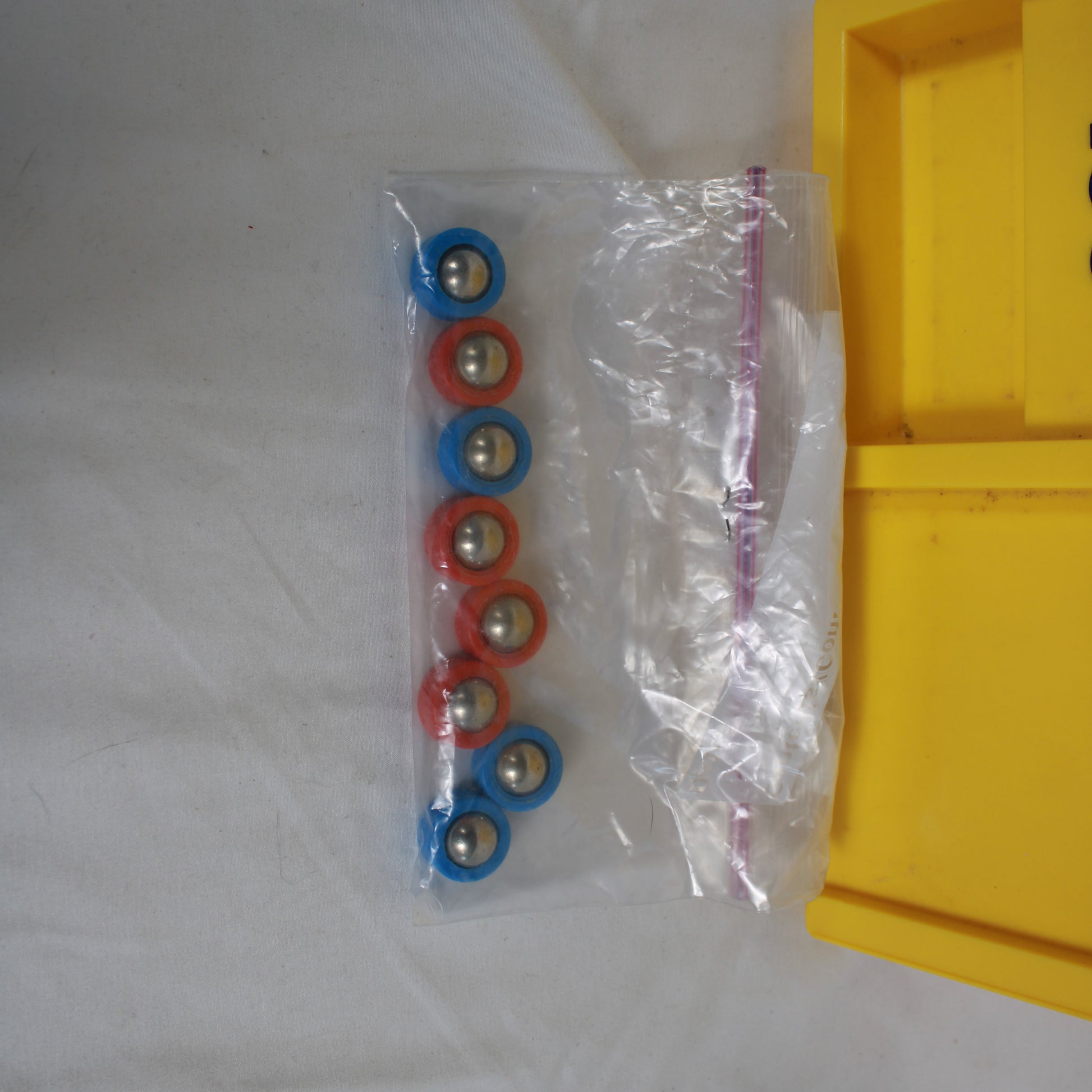 Packaged set of colorful bearings on a white surface with a yellow object partially visible.