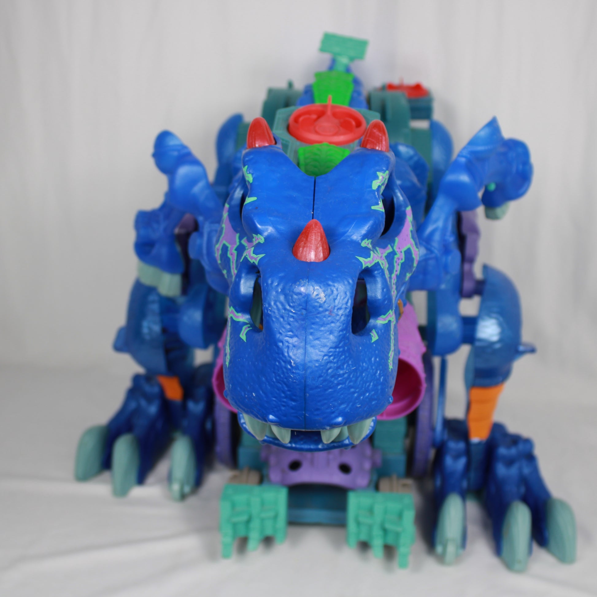Toy dinosaur with blue body, red mouth, and green accents on a white background