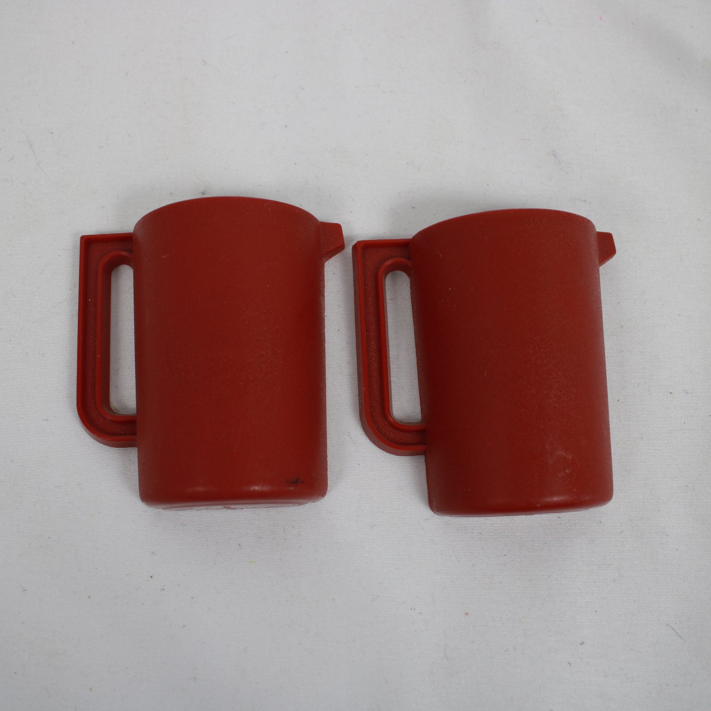 Two red plastic mugs on a light gray background