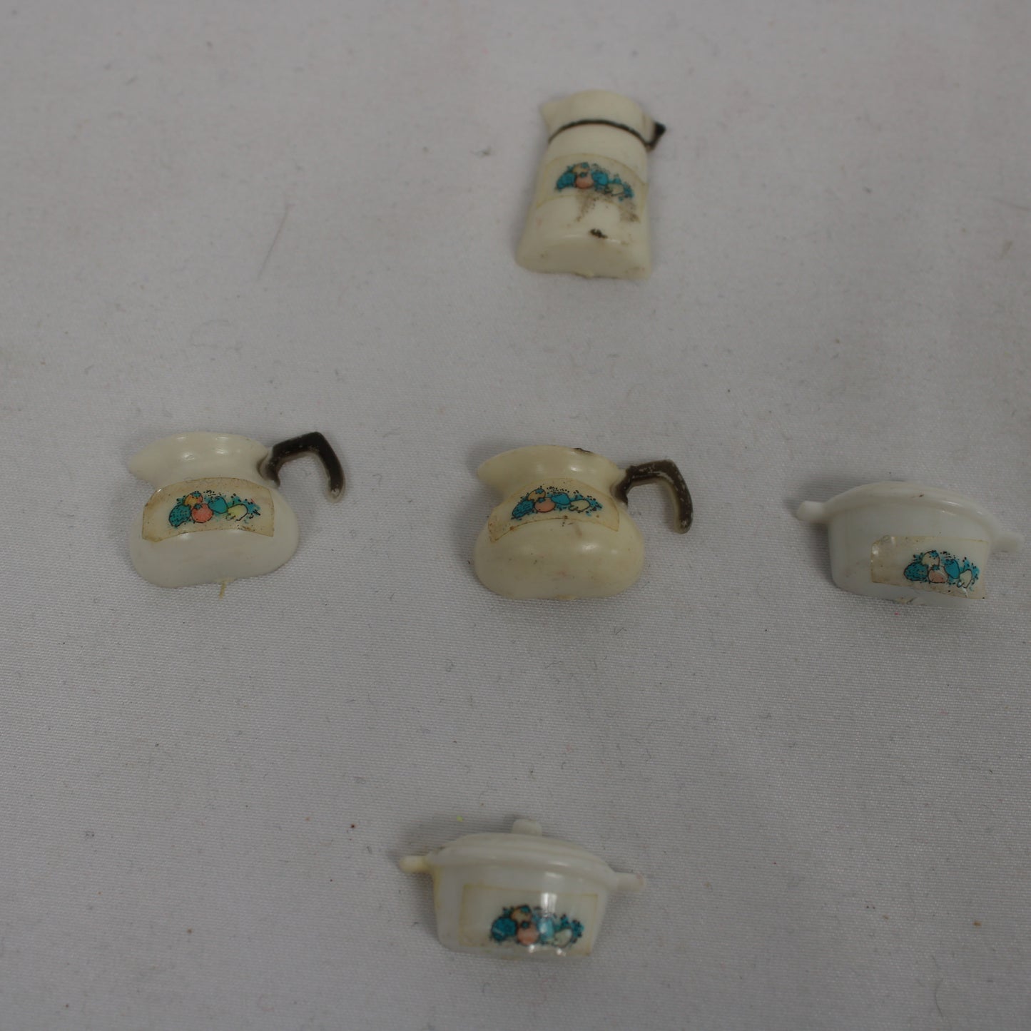 Set of miniature ceramic pots with decorative elements on a white background