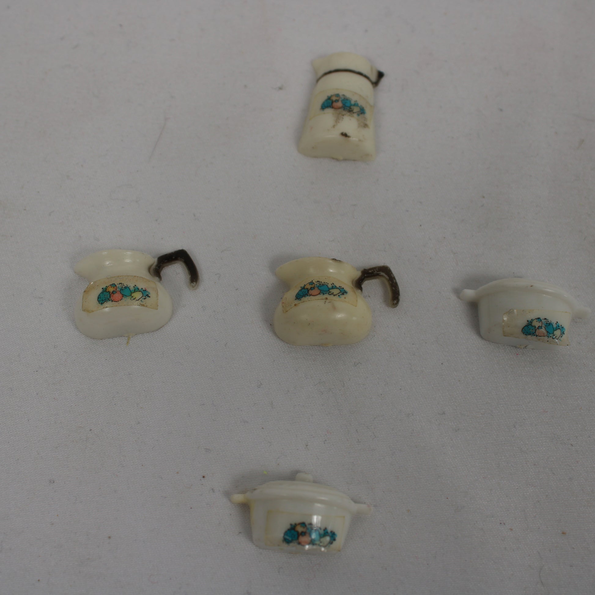 Set of miniature ceramic pots with decorative elements on a white background