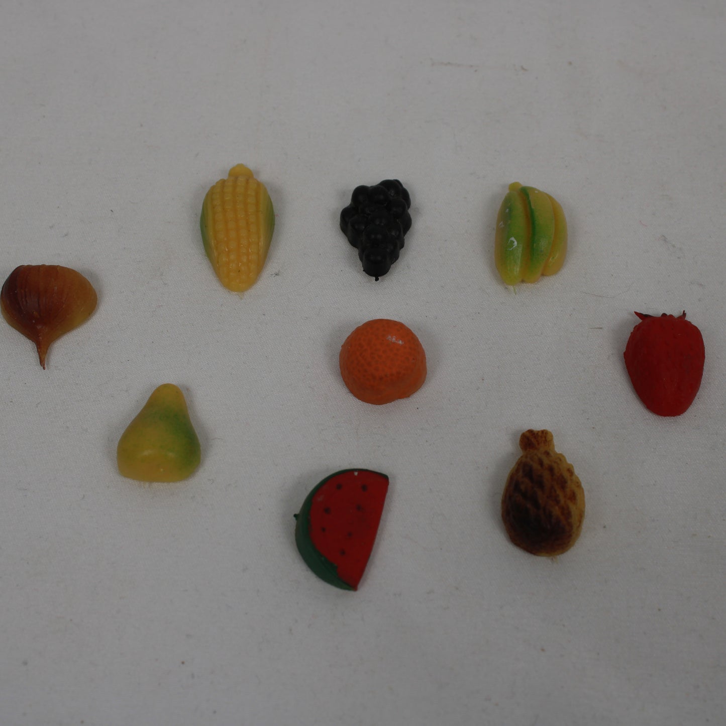 Assorted small fruit-shaped candies on a white background