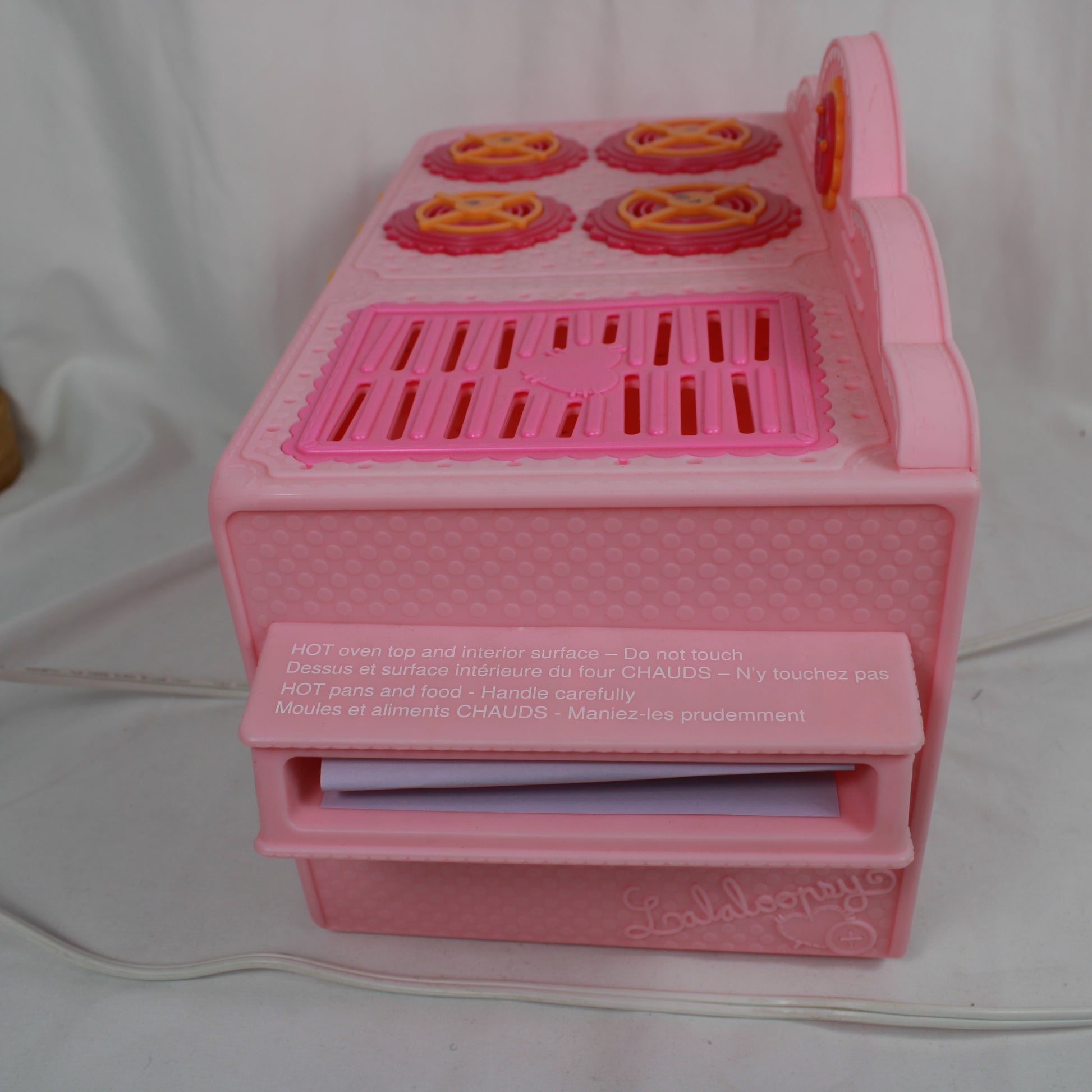 Pink toy stove with four burners on a white background
