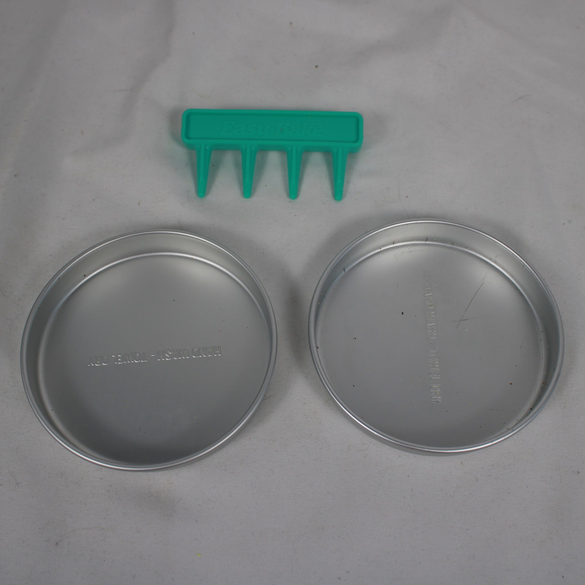 Two metal lids and a green plastic tool on a gray background