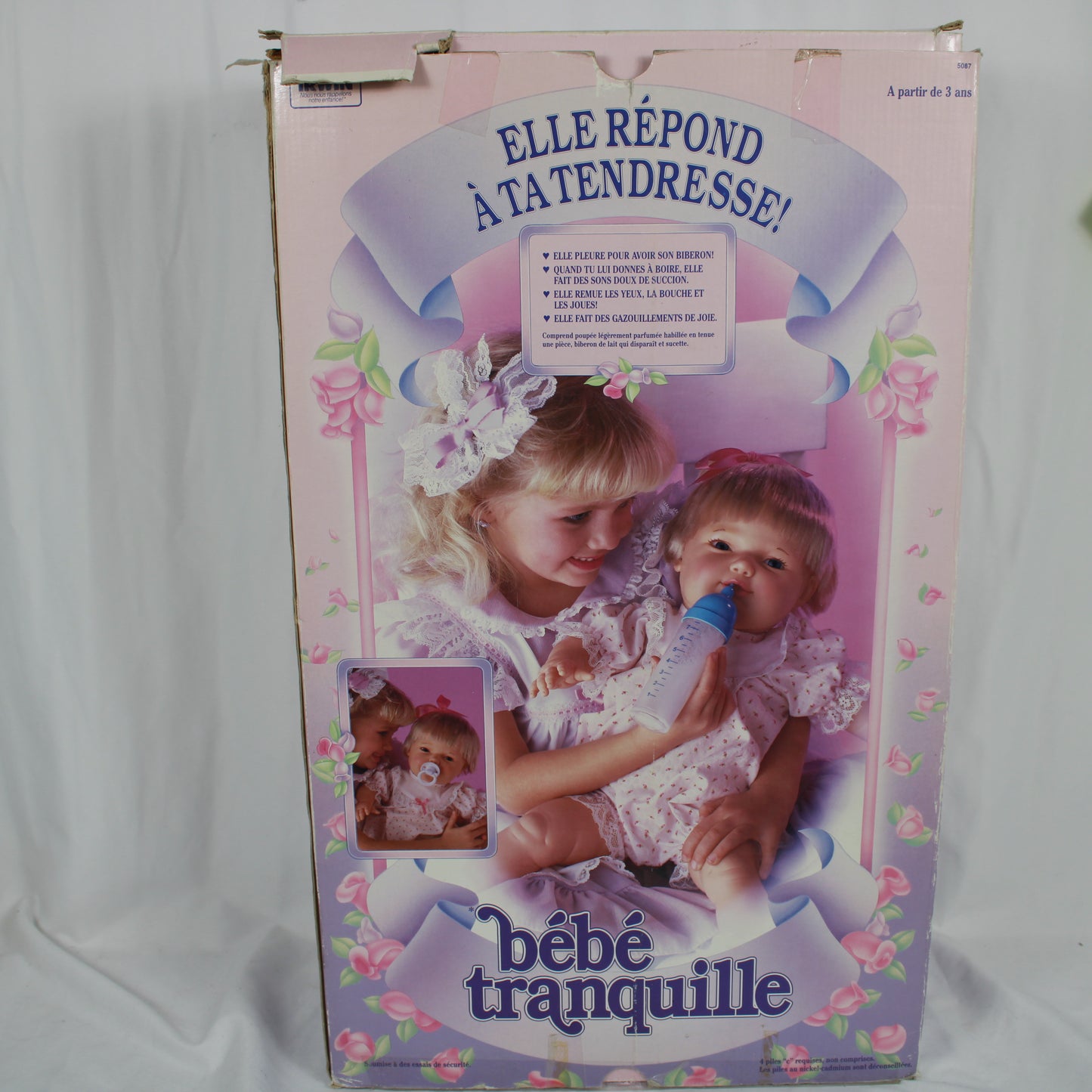 Vintage doll packaging with a child and doll, featuring text in French.