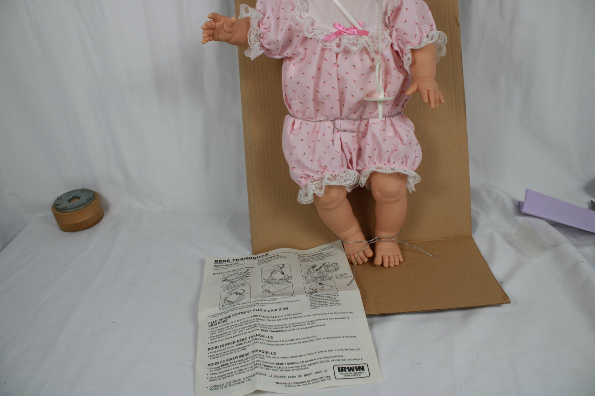 Vintage doll in pink outfit with cardboard backing and paper on a white background