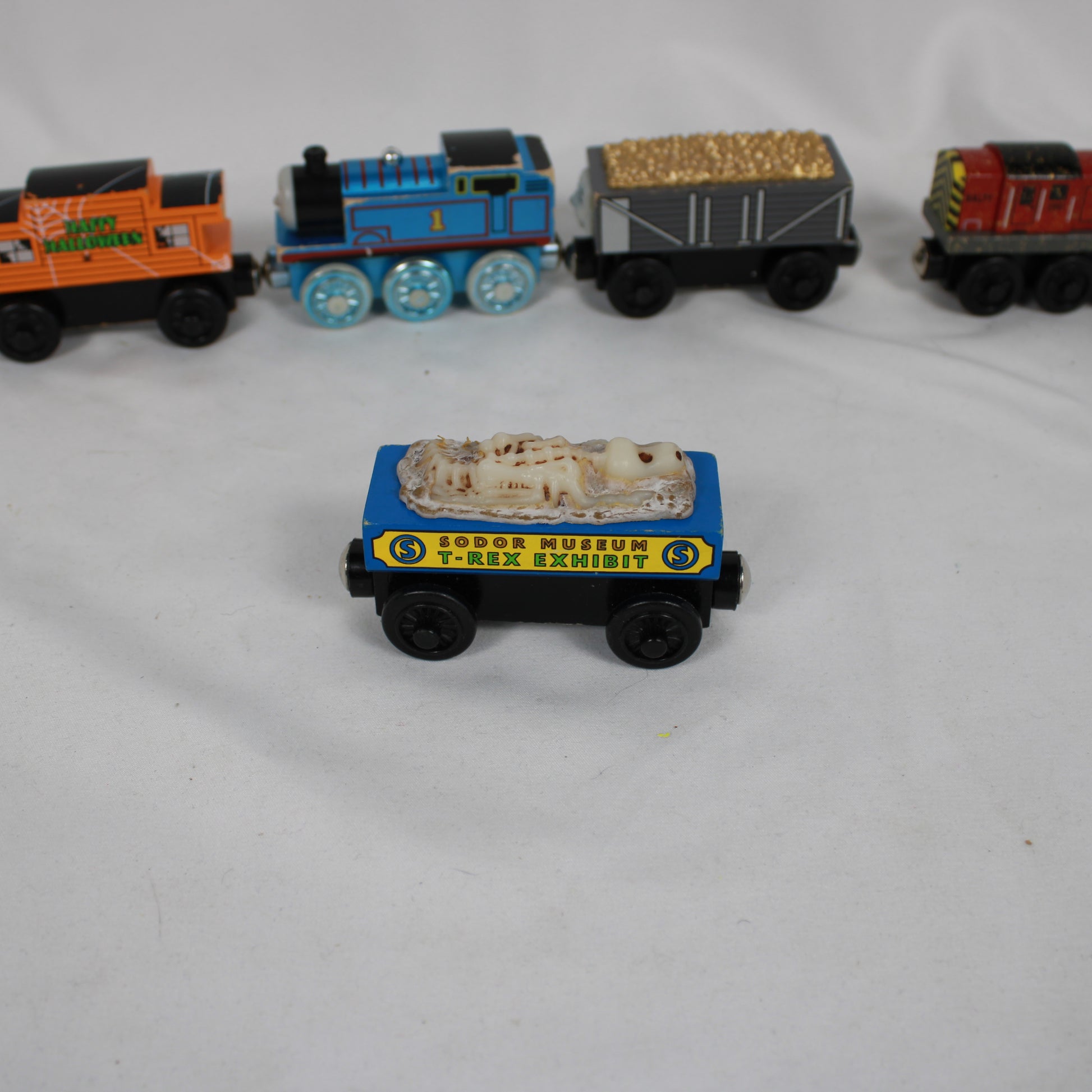 Toy train set with a blue engine and cargo car labeled 'Zooper Museum T-Rex Exhibit' on a white background.