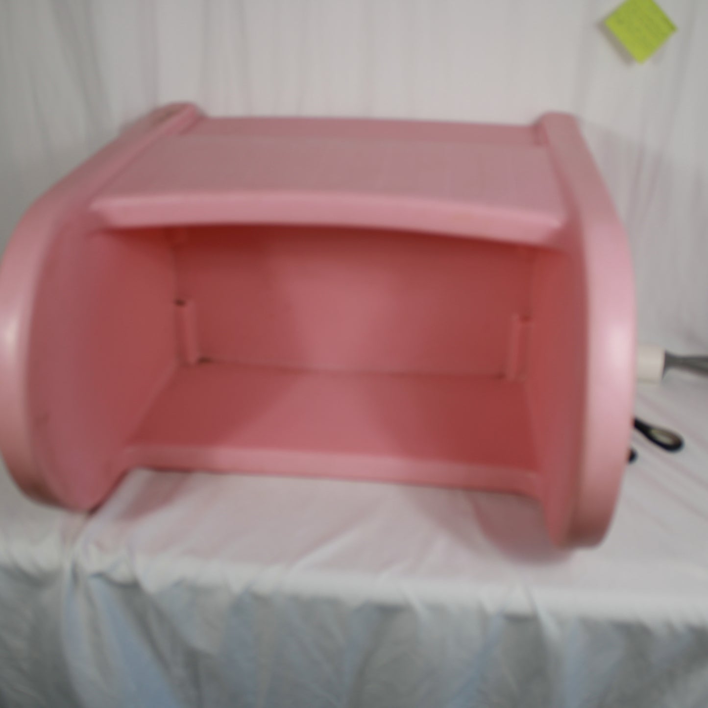 Pink plastic object on a white surface with a green label in the corner.