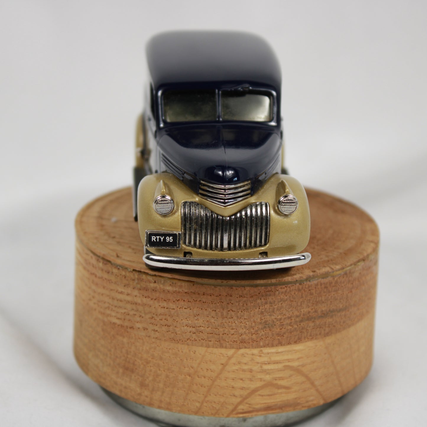 Model of a vintage car on a wooden base with a white background