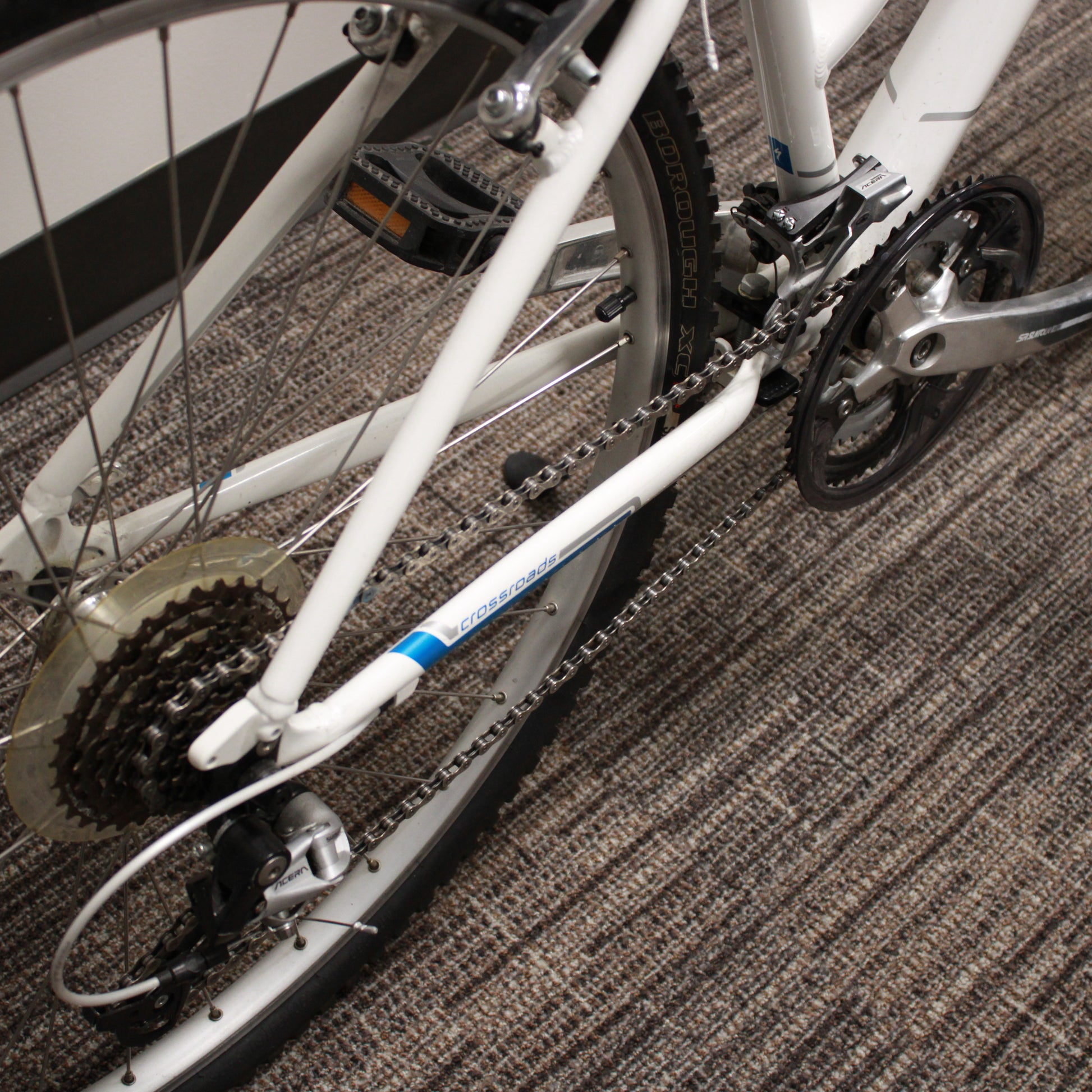 Close-up of a bicycle chain and gear system on a carpeted floor